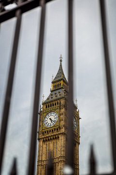 Horizontal view of the Big Ben tower seen behind bars on a dark day, UK