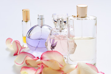 Perfume bottles with flower petals on light background. Perfumery, fragrance collection. Women accessories.