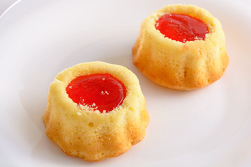 couple of the cookies with strawberry jam on the white plate. Time of tea