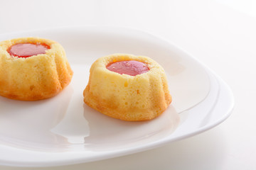 couple of the cookies with strawberry jam on the white plate. Time of tea