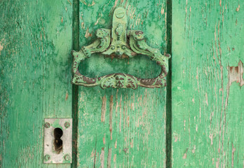 Closeup vintage antique Wooden door painted in worn green on a Country house door lock door handle and latch