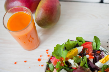 Fresh vegetable salad and freshly squeezed mango juice. Salad from arugula, black and red caviar, tomato, eggs, goat cheese, olive oil. Smoothies of mango, carrot, pumpkin. Vitamins, vegetarianism