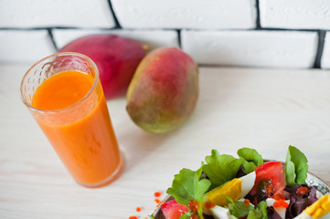 Fresh vegetable salad and freshly squeezed mango juice. Salad from arugula, black and red caviar, tomato, eggs, goat cheese, olive oil. Smoothies of mango, carrot, pumpkin. Vitamins, vegetarianism