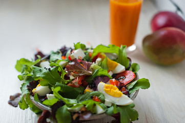 Fresh vegetable salad and freshly squeezed mango juice. Salad from arugula, black and red caviar, tomato, eggs, goat cheese, olive oil. Smoothies of mango, carrot, pumpkin. Vitamins, vegetarianism