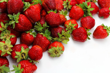 Ripe red strawberries scattered on a white background.