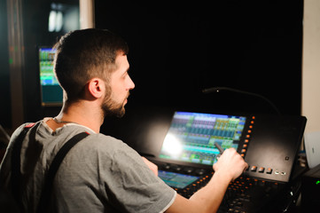 A lighting engineer works with lights technicians control on the concert show. Professional light...