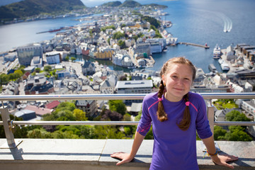 Fototapeta na wymiar smiling girl on a viewpoint with the view of Alesund at the background