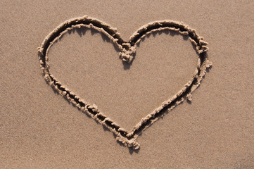 Heart drawn in the sand. Beach background.