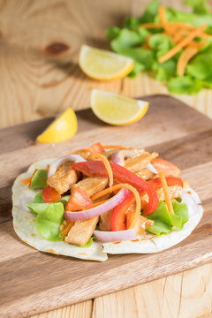 Grilled meat with onion and bell peppers, tomato,lettuce and serve with flour tortilla on wooden board.