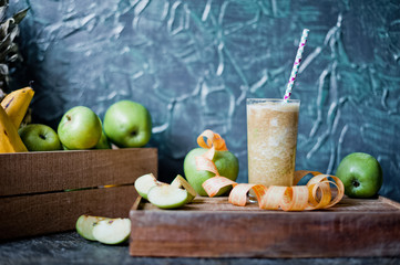 Vitamins, greens, vegetarianism, healthy food, sports. Apples, kiwi and smoothies from them on a dark background. Apple smoothies on a wooden tray with a centimeter. Bottle with black inscription for 