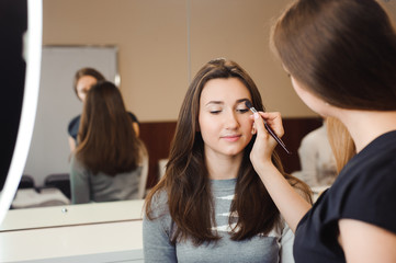 Make up artist doing professional make up of young woman. Beauty shcool.