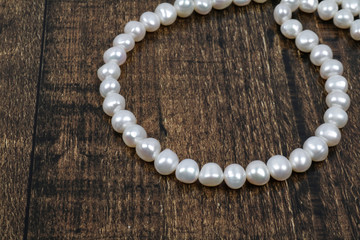 White pearls strand on the wooden background