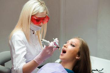 female doctor in uniform checking up female patient's teeth in dental clinic.