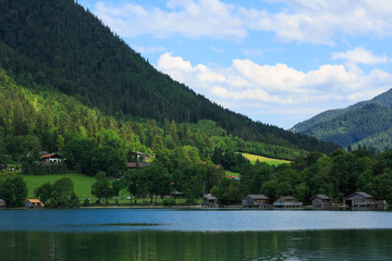 Idyllic mountain landscape in the Alps with lake, green meadows and mountains