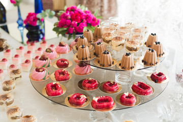 Delicious and tasty dessert table with cupcakes shots at reception closeup