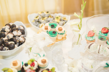 Delicious and tasty dessert table with cupcakes shots at reception closeup