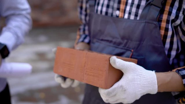 Brown brick in hands of builder. Close up view of builder hands