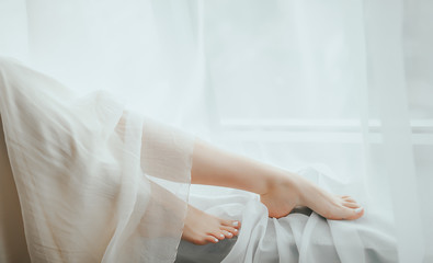 Fototapeta na wymiar Bride in a stylish dress sits on the window background. Legs and dress close-up