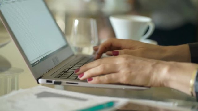 Businesswoman working on laptop sitting by glass table in office
