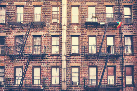 Old film retro style photo of a building with fire escape, one of New York City symbols, USA.