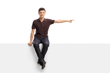 Teenage boy sitting on a panel and pointing right