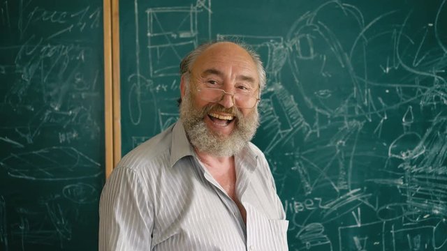 A charismatic old teacher laughing near the blackboard 4K
