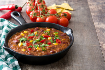 Traditional mexican tex mex chili con carne in a frying pan on wooden table
