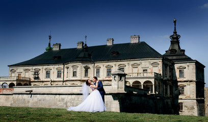 Bride and groom pose before beautiful old castle