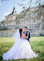 Wedding couple hugs before beautiful old castle