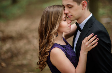 Man looks in woman's eyes standing with her in the forest