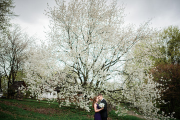 Stunning couple stands under large white tree with white flowers