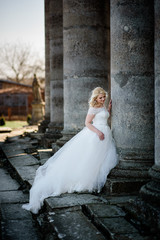 Obraz premium Blonde bride leans to an old stone column