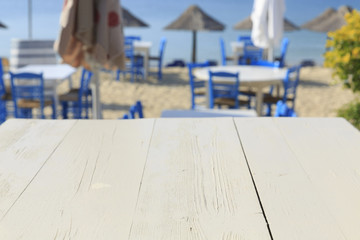 White wooden picnic table by the sea in Greece, Empty picnic table for product display, Defocused beach in the background