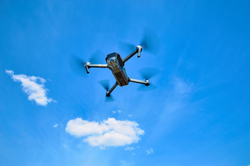 Flight of a gray quadrocopter against a blue sky.
