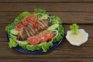 Grill pork sliced Salad on vegetable and pour with salad dressing in blue dish / Selective focus..