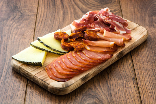 Spanish cold cuts (embutidos). Cheese, sausage and ham on wooden table
