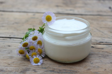 Fototapeta na wymiar Cosmetic cream with chamomile flowers