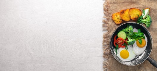 Fried egg with herbs, toast bread and vegetables in a frying pan. Top view. Free space.