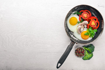 Fried egg with herbs and vegetables in a frying pan. Top view. Free space.