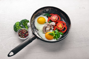 Fried egg with herbs and vegetables in a frying pan. Top view. Free space.