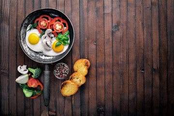 Fried egg with herbs, toast bread and vegetables in a frying pan. Top view. Free space.