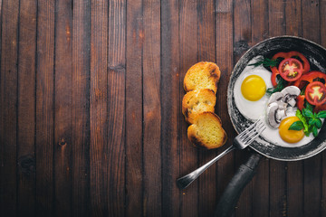 Fried egg with herbs, toast bread and vegetables in a frying pan. Top view. Free space.