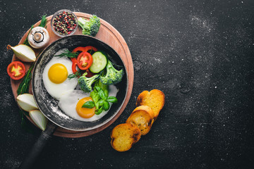 Fried egg with herbs, toast bread and vegetables in a frying pan. Top view. Free space.