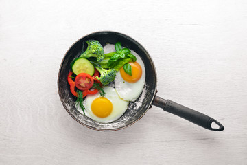 Fried egg with herbs and vegetables in a frying pan. Top view. Free space.