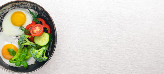 Fried egg with herbs and vegetables in a frying pan. Top view. Free space.