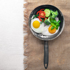 Fried egg with herbs and vegetables in a frying pan. Top view. Free space.