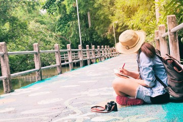 Young asian woman traveling and writing on notebook against beautiful tropical scenery