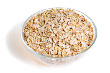 Uncooked oat flakes in glass bowl on white background. Healthy food. Close up, top view