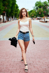 A girl is walking around the city. Travels. Street fashion. City center. Youth style of clothes.
