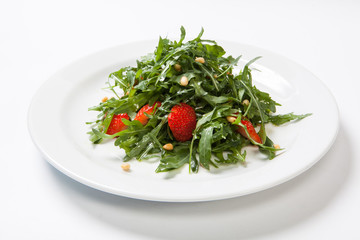 Useful strawberry salad with arugula nuts and honey on the white plate